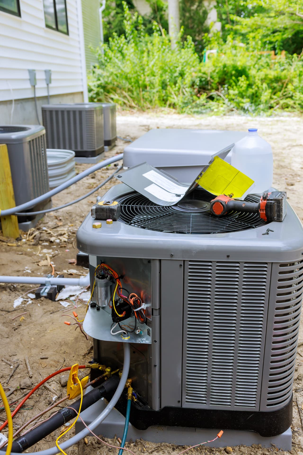 Outdoor air conditioning condenser opened for repair with technician tools on top