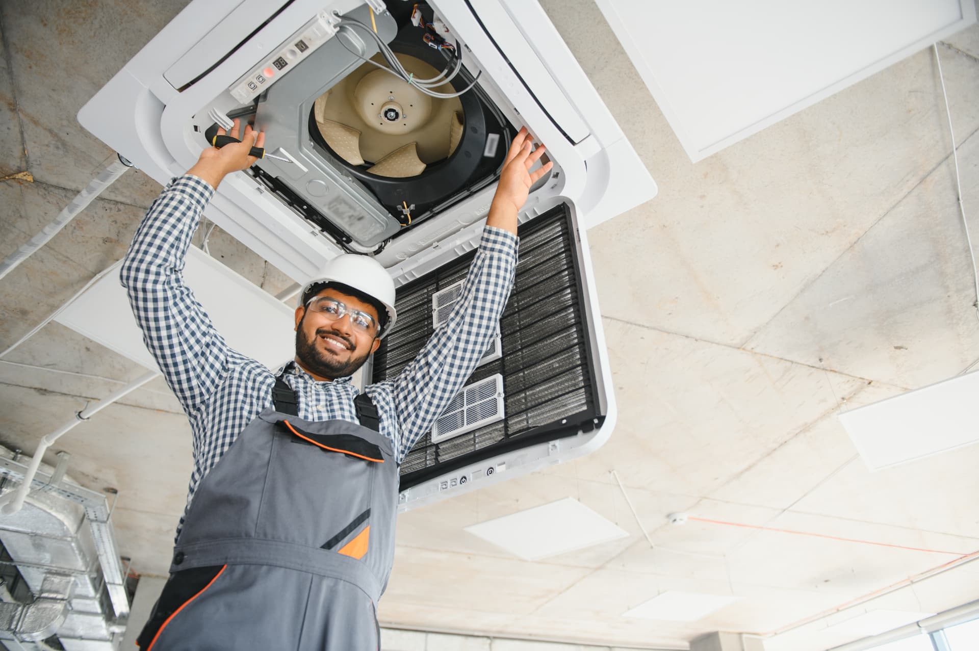 Technician installing a ceiling-mounted HVAC unit