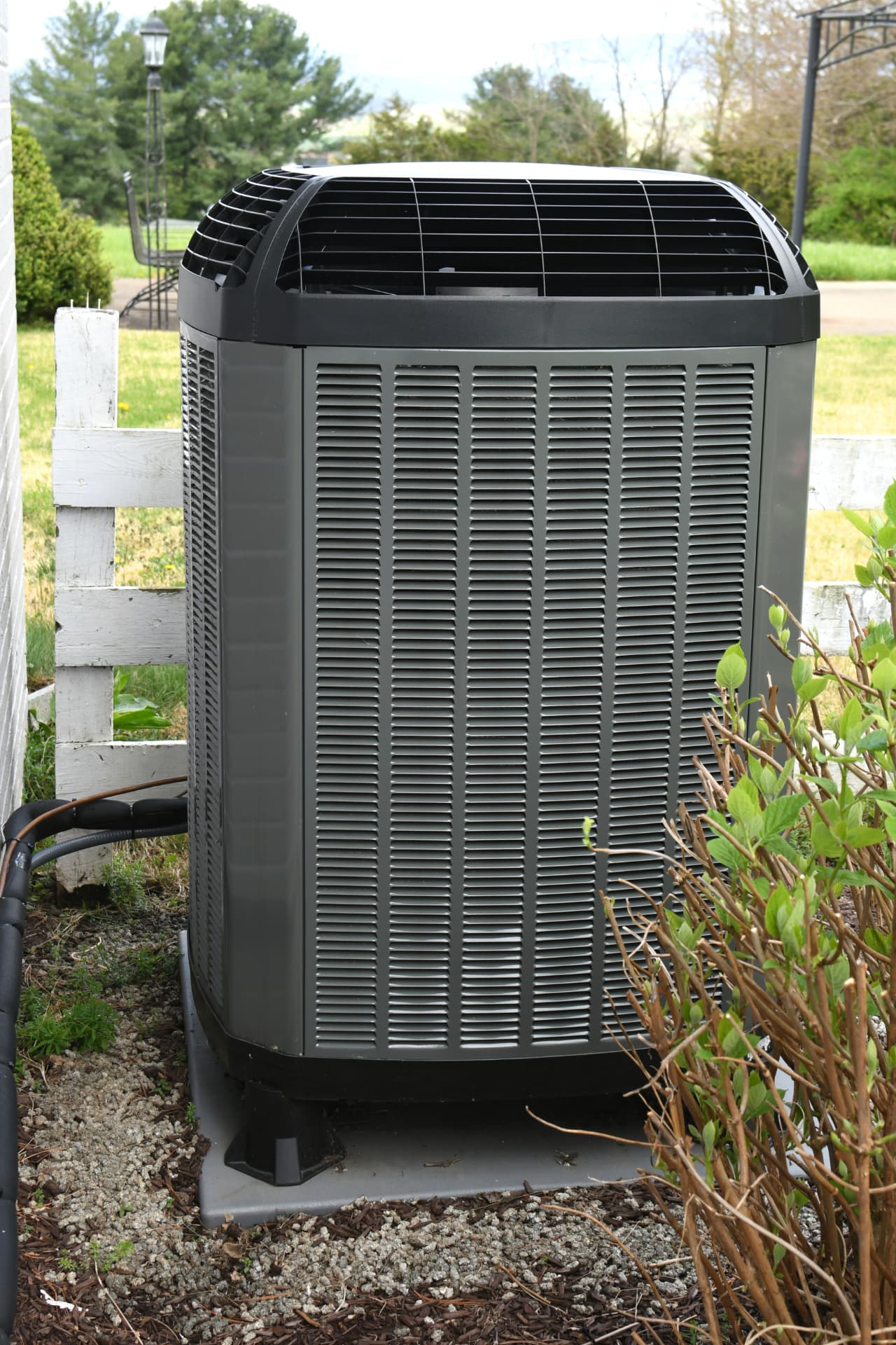 Outdoor air conditioning condenser beside a home